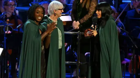 Former contestants Minah Shannon and Linda Rands with Claudia Winkleman on stage at the Proms in July 2025