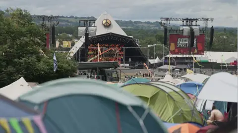 The iconic Pyramid Stage sits in the centre of the photo with screens either side and tents in front