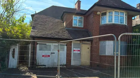 LDRS Boarded up house behind security fencing