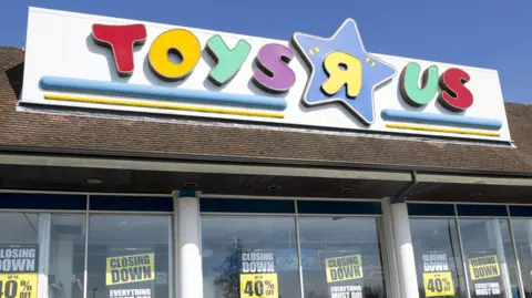 The colourful Toys R Us sign positioned above shop windows in which there are closing down signs