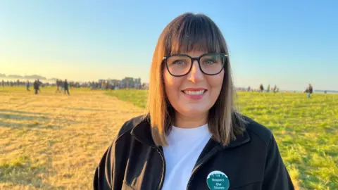 Kate Logan looks into the camera with stones and crowd behind her