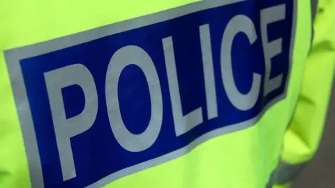 The back of a police officer's jacket. The word "police" is in silver letters on a blue background.