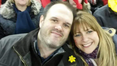 Sam Morgan Sam Morgan has short brown hair and dark eyes, Karen Morgan has dark blonde hair, a fringe and blue eyes. Sam is wearing a yellow daffodil on his dark coat, and Karen has a Welsh dragon painted on her cheek and is wearing a purple scarf