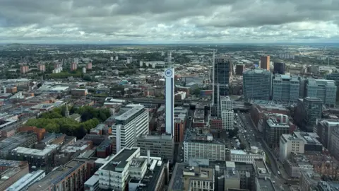We can see for miles across the city. We are high up. We can see the iconic BT tower surrounded by office buildings and other city centre landmarks. There are homes and structures as far as the eye can see.