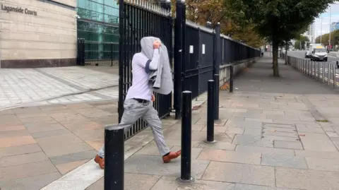 BBC Christopher Morrow leaving Laganside Court covering his head with his jacket