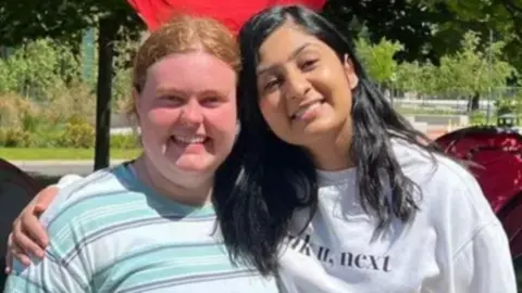 Councillor Grace Lewis Grace Lewis and Zarah Sultana hug while facing the camera and smiling.