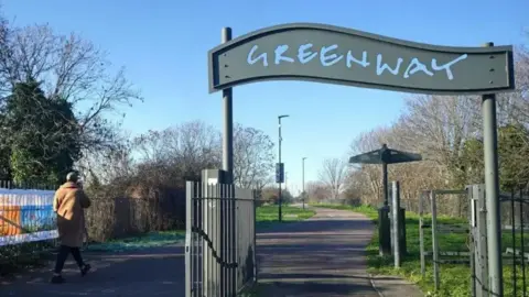 PA Media A view of the Greenway footpath with the name Greenway above an entrance and a passer-by walking along