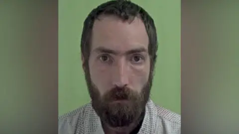 ISLE OF MAN CONSTABULARY Police mugshot of Hamon, who has short dark brown hair and a full beard.