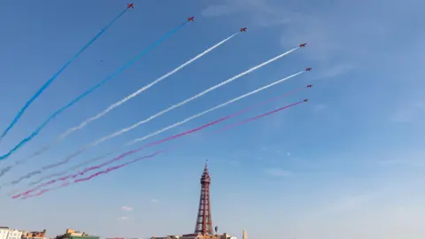 VisitBlackpool The Red Arrows fly over Blackpool Tower leaving red, white and blue vapour trails.