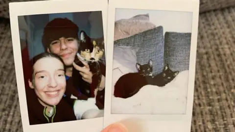 Leah Gregory Two polaroid photographs. One shows Leah Gregory and Paul Allsopp who is holding Skylar, the mother of Wolverine. Skylar is mainly black but has tortoiseshell colouring on much of her face. The other shows two black cats, Wolverine and his sister Catzilla, lying next to each other on a white rug with two grey cushions behind them.