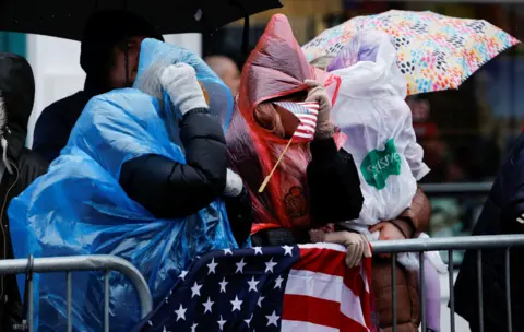 Reuters Two women wearing ponchos cower from the wind and rain as they wait to see Joe Biden