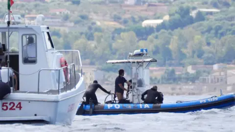 PA Police divers on a rigid inflatable boat, with a larger boat in the foreground. They are part of the recovery operation above the wreck of the luxury yacht, Bayesian.