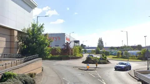 The Bentley Bridge area of Wolverhampton where a roundabout and supermarkets can be seen and retail buildings in the distance.