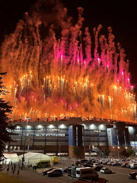 Brendan O'Hagan A view looking across to Hampden Park football stadium, with a huge amount of fireworks - mostly orange and pink - all exploding into the sky above the stadium. 