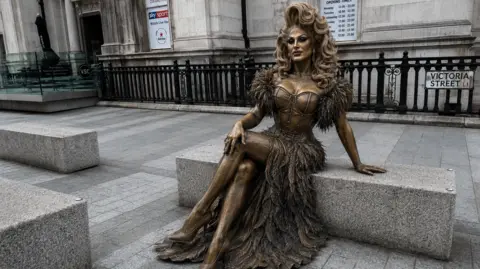 House of The Vivienne CIC/Proudly Said An AI image of the proposed life-size statue of The Vivienne on a concrete bench at the entrance to Liverpool's officially recognised Pride Quarter