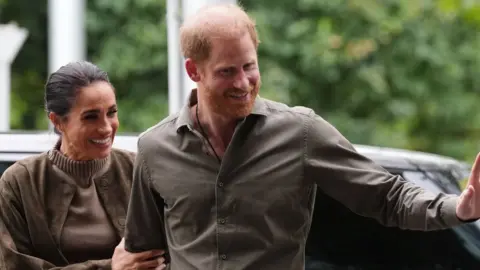 A ginger man and dark haired woman step out of a car.