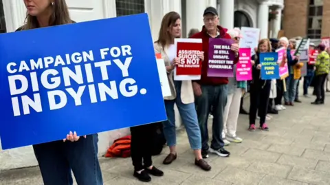 Campaigners with placards for and against the Assisted Dying Bill gather outside the Isle of Man's white parliament building.