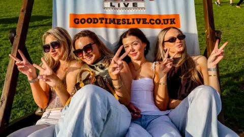 Good Times Festival Four young women sitting in an oversized deck chair at Good Times Festival. They are posing for a picture, smiling at the camera and showing peace signs.