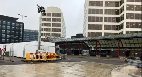 An old building with scaffolding and yellow barriers.