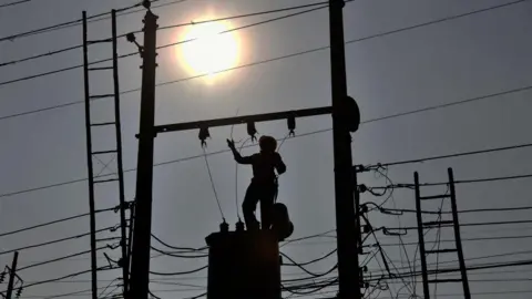 A worker works on an electric transmitter at Keraniganj area in Dhaka, Bangladesh 