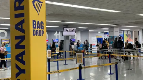 Cameron Noble/BBC Passengers queuing at Ryainair check-in desks at Norwich Airport