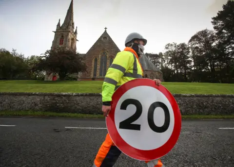 Scottish Borders Council A man carrying a 20mph sign in front of a church
