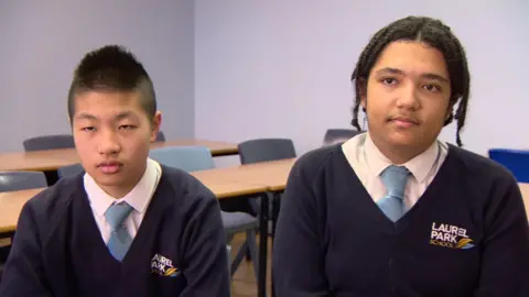 Two teenaged boys in school uniform in a classroom