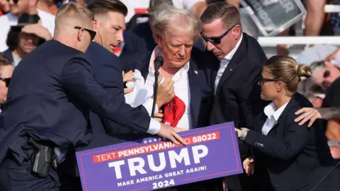 Reuters Republican presidential candidate and former U.S. President Donald Trump is assisted by the Secret Service after gunfire rang out during a campaign rally at the Butler Farm Show in Butler, Pennsylvania, U.S., July 13, 2024. 