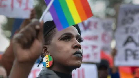 AFP A PROTESTER mengibarkan bendera pelangi selama pawai oleh komunitas LBTQ di University of Cape Town pada Juli 2023.