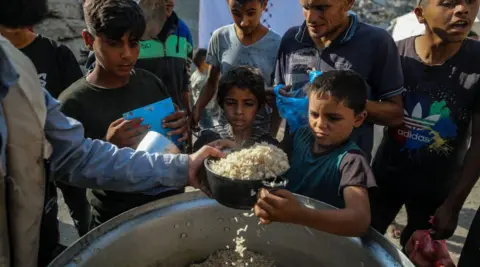 EPA Two Palestinian boys receive a bowl of rice