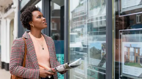 Woman looks in estate agency window 