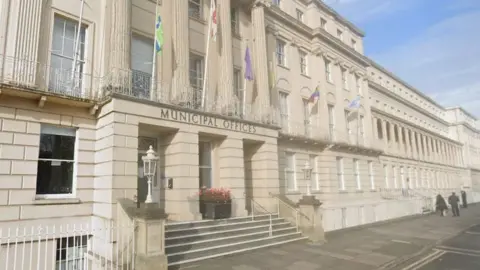 The municipal offices in Cheltenham. A beige building with stairs leading to the entrance.