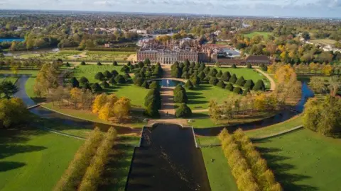 Historic Royal Palaces An aerial view of the garden at Hampton Court Palace, which features lakes and trees in structured patterns.