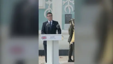 UK Prime Minster Andy Burnham stands behind a podium in Kyiv, Ukraine.