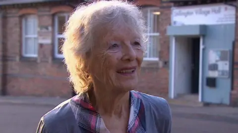 Judith Turner stands smiling outside Stillington Village Hall