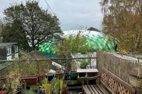 BBC Taman balkon dengan lapangan tenis tiup di latar belakang.