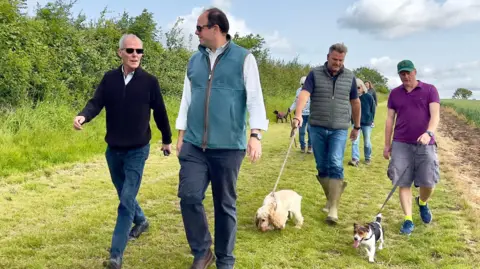Greg Smith MP MP Greg Smith with walkers crossing a rural field