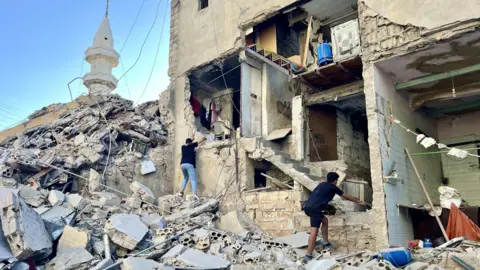 People from the Environmental Protection Agency inspect a damaged building after an Israeli raid on Tyre, Lebanon (October 23, 2024)