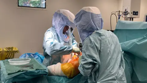 A patient having a hip replaced with surgeons in an operating theatre.