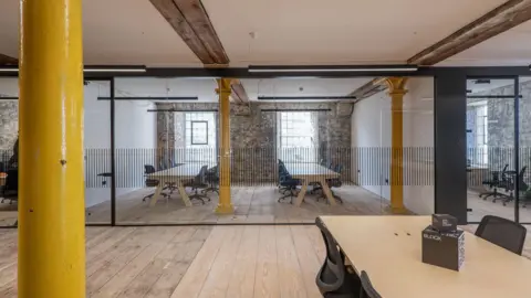 Gillespie Yunnie Architects An office space with wooden floors and yellow painted original iron pillars