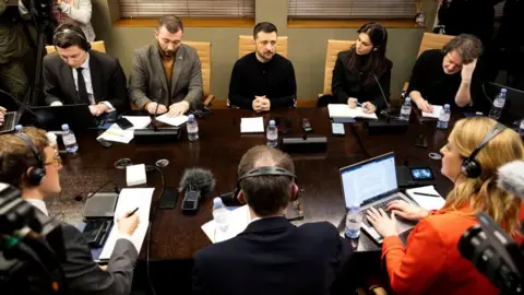 Reuters Voludmir Zelinski (the central back row wearing a black military shirt) speaks to a group of UK journalists on Sunday, including Laura Quinzberg from the BBC (below the right), who can be seen writing on a laptop computer