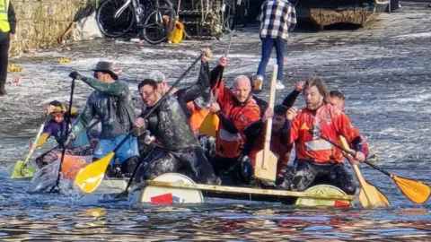 Scarborough Sub Aqua Club Several people on board a racing raft with awes in their hands. 