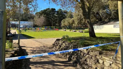 Jenny Kirk/BBC An area of Sparrows Nest Gardens. There is white and blue police tape cordoning off an area.