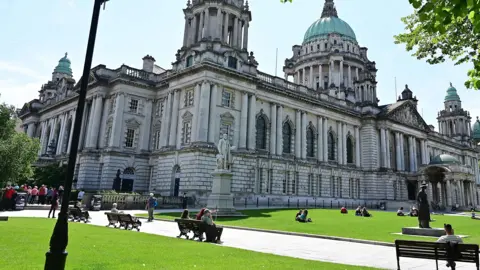 People sitting at Belfast City Hall on a sunny day