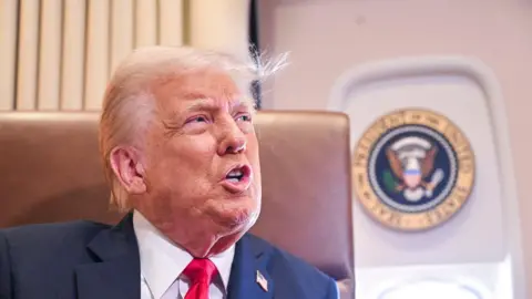 Getty Images Trump speaking to reporters on Air Force One prior to the Super Bowl, a presidential seal is in the background