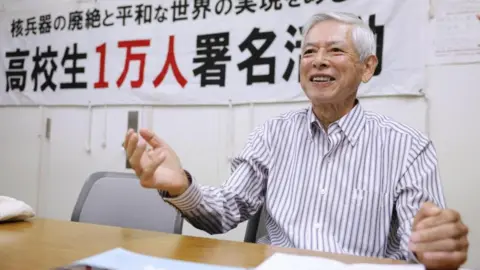  Reuters A smiling man in a striped shirt sits at a table.