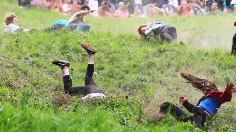 Getty Images Competitor's in the women's race at the Gloucestershire cheese rolling are seen tumbling down Cooper's Hill