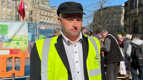 Tom MacDougall/BBC Joel Mayfield, wearing a Unite-branded hi-vis jacket.