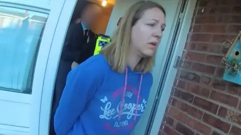 Screen grab taken from body worn camera footage issued by Cheshire Constabulary of the arrest of Lucy Letby. She is wearing a blue Lee Cooper hoody and has shoulder length blonde hair. 