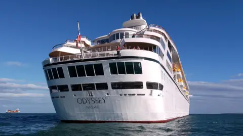 BBC Stern of the Villa Vie Odyssey cruise ship off shore in Belfast lough on a sunny day. Passengers are looking overboard.